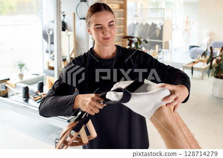 Physiotherapist Assisting A Patient With Foot Therapy in a Modern Clinic Physiotherapist Assisting A Patient With Foot Therapy in a Modern Clinic 128714279