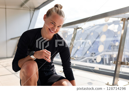 Confident woman smiling during an outdoor workout with urban background 128714296
