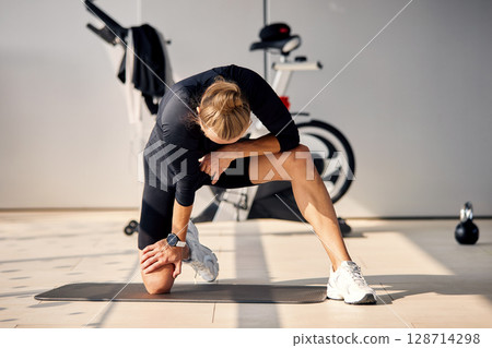 Active individual stretching on mat in modern gym environment with equipment 128714298