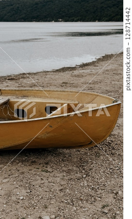 Yellow Boat on Rocky Lakeshore 128714442
