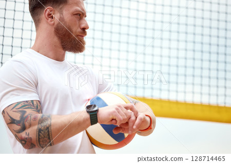 Athlete holding volleyball with net backdrop and focused expression outdoors Athlete holding volleyball with net backdrop and focused expression outdoors 128714465