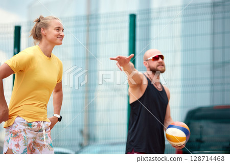 Two adults enjoying an outdoor volleyball match under the bright sun Two adults enjoying an outdoor volleyball match under the bright sun 128714468