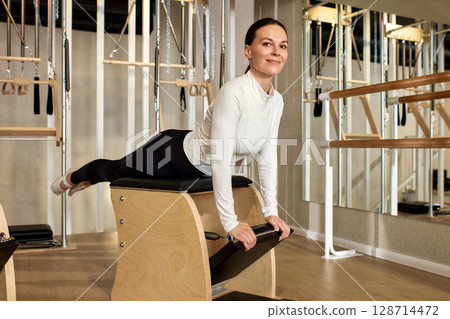 Woman Practicing Pilates on Equipment in a Modern Fitness Studio 128714472