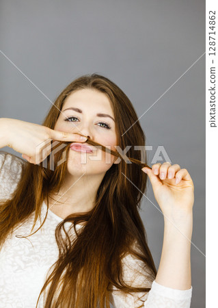 Woman having fun with her hair making moustache Woman having fun with her hair making moustache 128714862