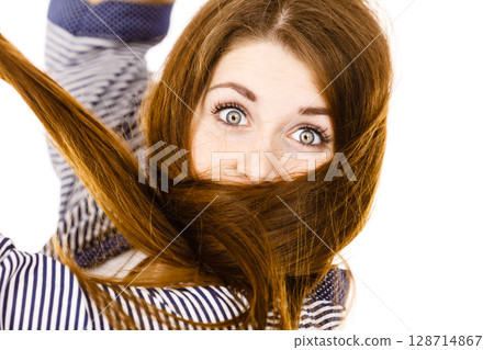 Woman having face covered with her brown hair Woman having face covered with her brown hair 128714867