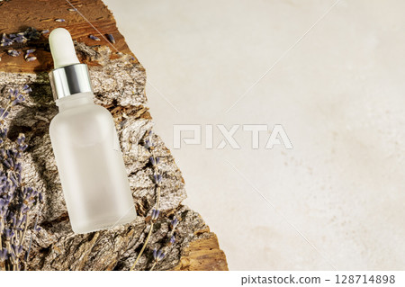 Natural beauty care concept. Organic serum oil cosmetics bottle on wooden podium with lavender flowers on neutral beige background with copy space. Body skin, face treatment product composition Natural beauty care concept. Organic serum oil cosmetics bottle on wooden podium with lavender flowers on neutral beige background with copy space. Body skin, face treatment product composition 128714898