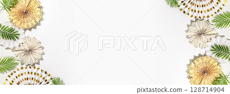 Holidays banner with holiday paper decoration and palm leaves on a white background with copy space. Party, carnival or festival background. Birthday or wedding concept. Flat lay, banner size Holidays banner with holiday paper decoration and palm leaves on a white background with copy space. Party, carnival or festival background. Birthday or wedding concept. Flat lay, banner size 128714904