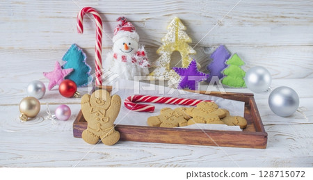 Christmas gingerbread cookies in the shape of a snowman on a white wooden background. Christmas decorations. Christmas gingerbread cookies in the shape of a snowman on a white wooden background. Christmas decorations. 128715072