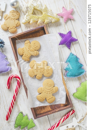 Christmas gingerbread cookies in the shape of a snowman on a white wooden background. Christmas decorations. Top view, flat lay. Christmas gingerbread cookies in the shape of a snowman on a white wooden background. Christmas decorations. Top view, flat lay. 128715075