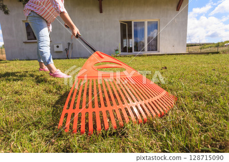 Unusual angle of woman raking leaves Unusual angle of woman raking leaves 128715090