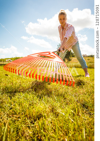 Unusual angle of woman raking leaves Unusual angle of woman raking leaves 128715091
