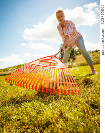 Unusual angle of woman raking leaves Unusual angle of woman raking leaves 128715092