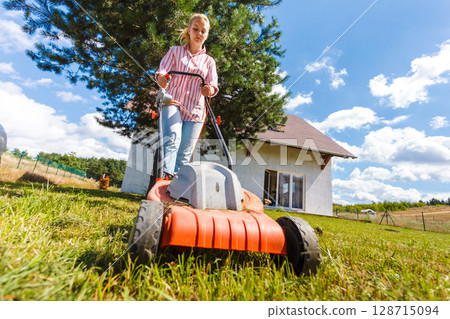 Woman mowing green grass Woman mowing green grass 128715094