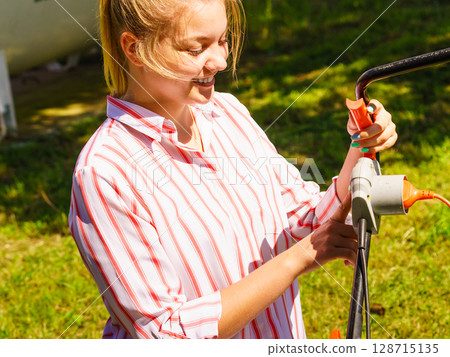 Woman being mowing lawn with lawnmower Woman being mowing lawn with lawnmower 128715135