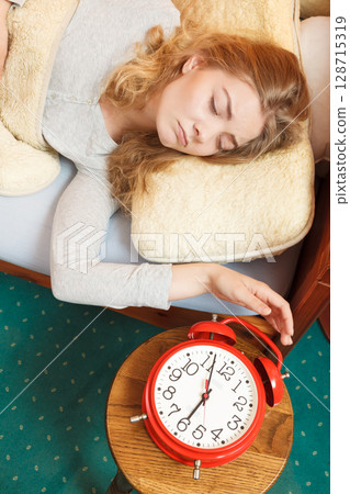 Woman waking up turning off alarm clock in morning 128715319