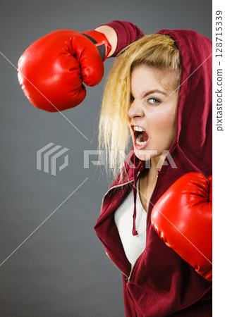 Angry woman wearing boxing gloves 128715339