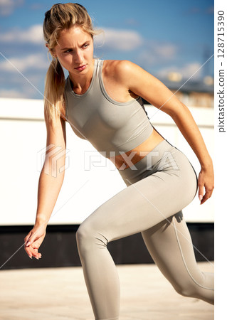Female athlete in activewear exercising outdoors under the bright blue sky 128715390