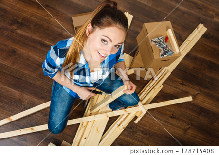 Woman moving into apartment assembly furniture. 128715408