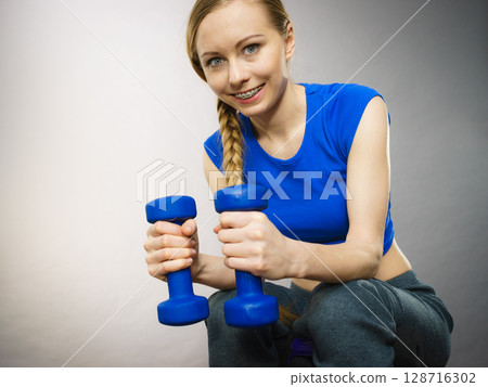 Teenage woman working out at home with dumbbell Teenage woman working out at home with dumbbell 128716302