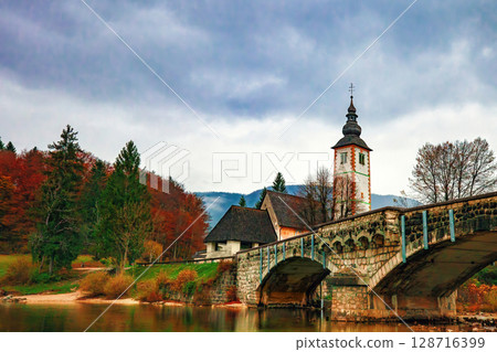 Autumn Bohinj lake,, bridge and Church of St. John the Baptist at sunset in Slovenia Autumn Bohinj lake,, bridge and Church of St. John the Baptist at sunset in Slovenia 128716399