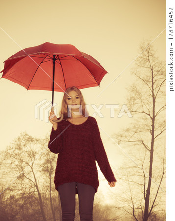 Fashion woman with umbrella relaxing in fall park. Fashion woman with umbrella relaxing in fall park. 128716452