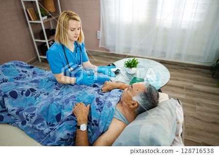 A dedicated nurse assists an elderly patient in recovery A dedicated nurse assists an elderly patient in recovery 128716538