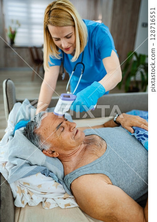 Nurse carefully monitors health of senior man in bed Nurse carefully monitors health of senior man in bed 128716551