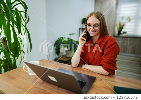 Smiling professional engaged in a call while working from home 128716579