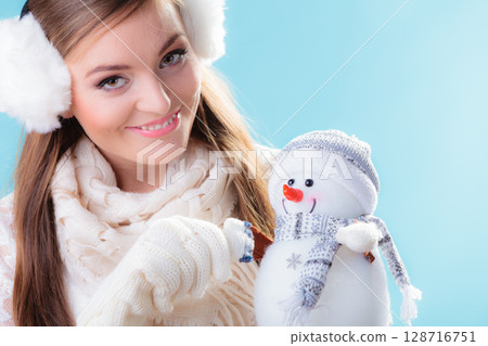 Woman in warm clothes holding snowman toy. 128716751