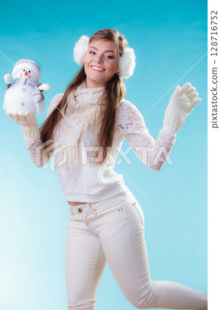 Woman in warm clothes holding snowman toy. Woman in warm clothes holding snowman toy. 128716752