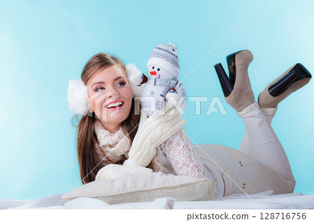 Woman in warm clothes holding snowman toy. 128716756