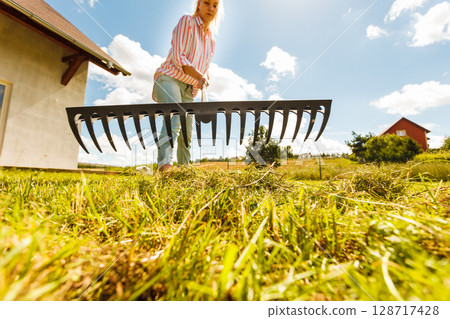 Unusual angle of woman raking leaves 128717428