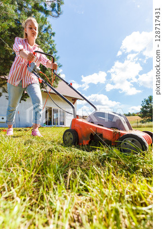Woman mowing green grass Woman mowing green grass 128717431
