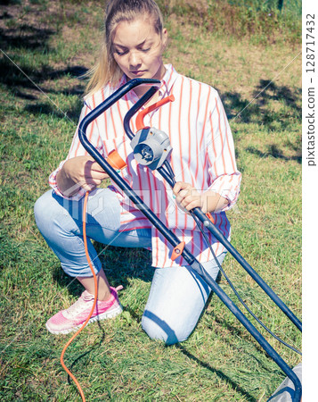 Woman mowing green grass Woman mowing green grass 128717432