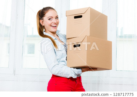 Happy woman moving into house carrying boxes. Happy woman moving into house carrying boxes. 128717775