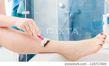 Woman shaving legs with razor in bathroom Woman shaving legs with razor in bathroom 128717809