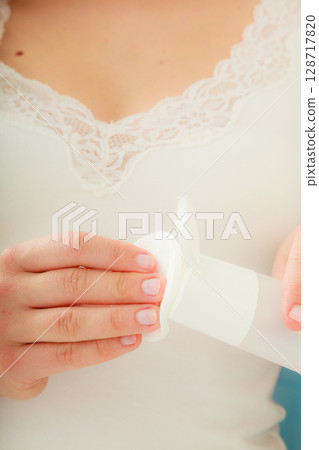 woman holding cotton swab and makeup remover in hands woman holding cotton swab and makeup remover in hands 128717820