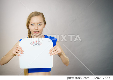 Teenage woman holding bathroom scale machine 128717853