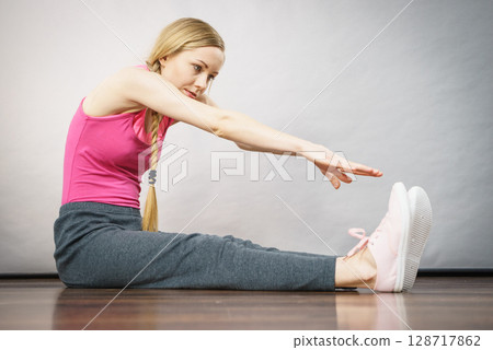Woman in sportswear sitting on ground 128717862