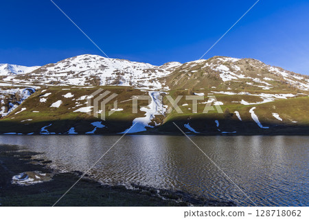 Lago della Rovina reflecting snowy mountains in Piedmont, Italy 128718062