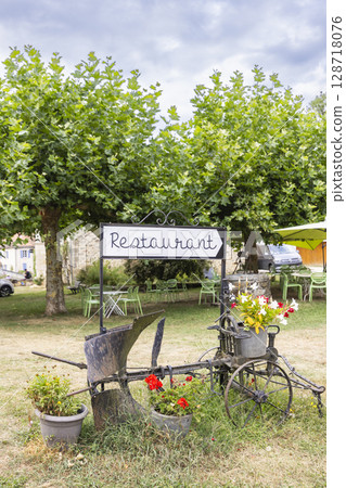 Restaurant sign and old plow decorating Saint Jean de Cole garden in Dordogne, France 128718076