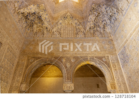 Moorish arches and intricate stucco ceiling decorating Alhambra in Granada, Spain 128718104