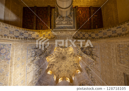 Ornate moorish ceiling and column rising towards intricate wooden door in Alhambra, Granada, Spain 128718105