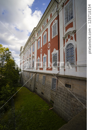 Broumov Monastery rising above retaining wall in Czechia under cloudy sky 128718154