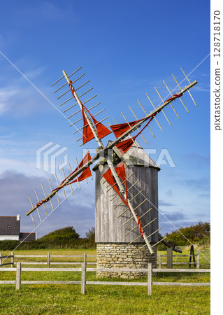 Traditional windmill with red sails on a sunny day in Brittany, France 128718170