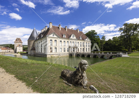 Chateau de Commarin reflecting in the moat with a sphinx statue in the foreground in Burgundy, France 128718209