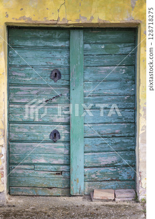 Rustic green door with peeling paint on a yellow wall Rustic green door with peeling paint on a yellow wall 128718275