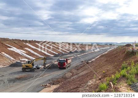 Excavator loading gravel into truck during highway construction in Czechia 128718314