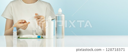 Night Contact Lens Care. Ophthalmology banner, boy clean contact lenses with cleansing solution. Concept of eye care and good vision. Mockup of multipurpose solution for lenses. Soft focus, copy space Night Contact Lens Care. Ophthalmology banner, boy clean contact lenses with cleansing solution. Concept of eye care and good vision. Mockup of multipurpose solution for lenses. Soft focus, copy space 128718371