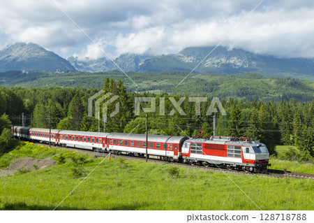 Electric passenger train passing through the green valley of Strba in Slovakia 128718788
